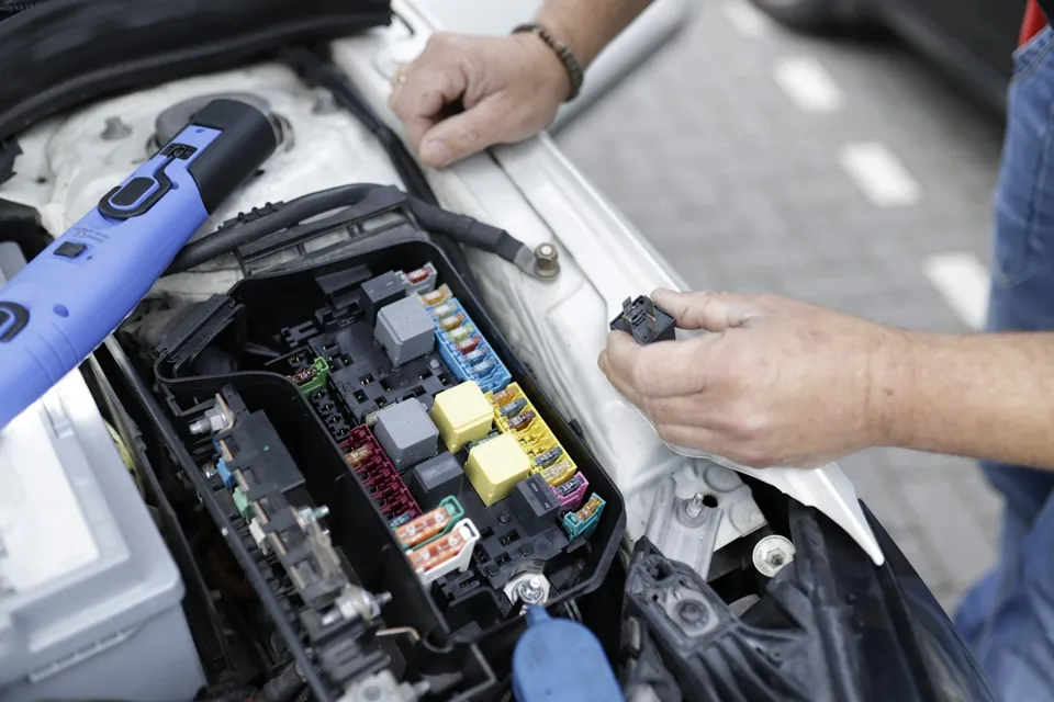 Technician checking a car engine and electrical components